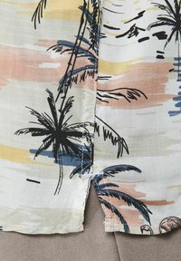Camicetta a maniche corte in tessuto leggero, con una palette di colori pastello, decorata con stampe di palme e sottili motivi astratti.