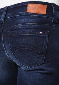 Donkerblauwe denim jeans met een rechte snit. Kenmerken zijn een leren logopatch en stikseldetails op de zakken.