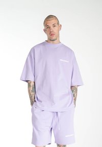 Lavendel bomulds t-shirt og shorts sæt med afslappet pasform, korte ærmer og et lille hvidt "MULTIPLY" logo på brystet og shortsene.
