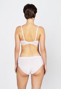 Soutien-gorge en dentelle rose clair avec bretelles réglables et fermeture à crochets, associé à une culotte en coton sans coutures assortie. Texture douce et finition lisse.