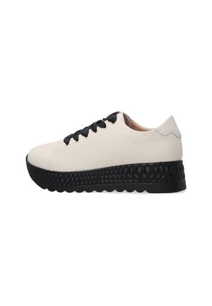 White leather sneaker with a textured black sole, featuring black laces and a smooth back. Side view highlights the contrasting elements.