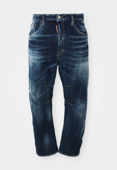 Tamno plavi traperice od denima s istrošenim pranjem, dizajn s pet džepova, patentni zatvarač i kontrastni šavovi. Sadrže blago oštećenje na koljenima.