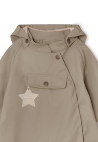 Beige børnejakke med hætte, trykknapper, forlommer og et stjernenformet mærke. Materialet ser blødt og vandafvisende ud.