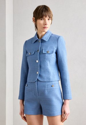 Blauw textuurjack met een kraag, voorzakken en zilveren knopen, gecombineerd met bijpassende blauwe shorts. Gladde stof, op maat gemaakte pasvorm.