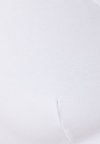 Tela de algodón blanca con una textura suave, que presenta costuras cosidas y un diseño de contorno sutil. Sin hardware o patrones visibles.