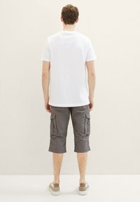 Weißes T-Shirt mit Rundhalsausschnitt, graue Cargo-Shorts mit seitlichen Taschen und hellfarbige Sneaker. Einfaches Design und baumwollähnliche Textur.