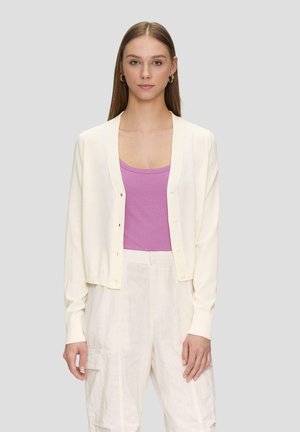 Cremfarbener Cardigan mit geripptem Kragen und fünf Knöpfen, über einem rosa gerippten Tanktop getragen. Das Model trägt hellfarbene, locker sitzende Hose.