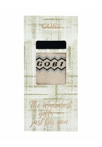 Beige kashmirstrumpor med svart zigzag-mönster och "GOBI"-bokstäver, förpackade på ett texturerat grönt och vitt kort med svart förslutning.