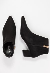 Botas de tobillo de ante negro con punta afilada, tacón bajo cuadrado, cierre de cremallera lateral y diseño minimalista. Logo visible en el interior.