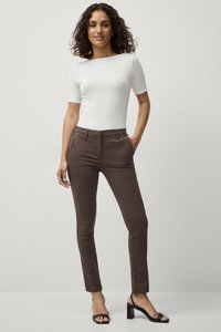 Bruin op maat gemaakte broek met een slim fit, voorzien van een middelhoge tailleband en een plooi-detail, gecombineerd met een aansluitend wit T-shirt met korte mouwen.