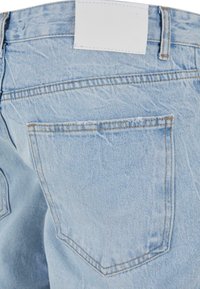 Svetlo modri jeans z zmernim pranjem, vsebujejo en zadnji žep in prazno belo oznako na pasu.