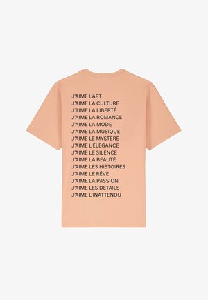 Pfirsichfarbene T-Shirt mit kurzen Ärmeln, das auf der Rückseite schwarzen Text mit verschiedenen Phrasen in Französisch zeigt. Reguläre Passform, aus Baumwolle.