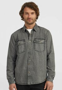 Denim shirt in a faded gray color. Features button closure, two chest pockets, and a classic collar. Textured fabric with visible stitching.