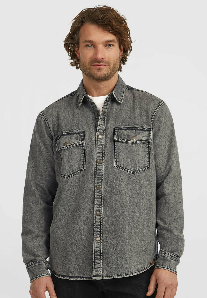 Denimskjorte i en falmet grå farve. Har knaplukning, to brystlommer og en klassisk krave. Tekstureret stof med synlige sømme.