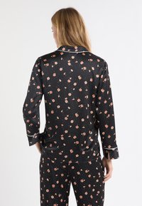 Czarny zestaw piżamowy w kwiatowy wzór z satynowym wykończeniem, długimi rękawami, białym obszyciem i luźnym krojem.