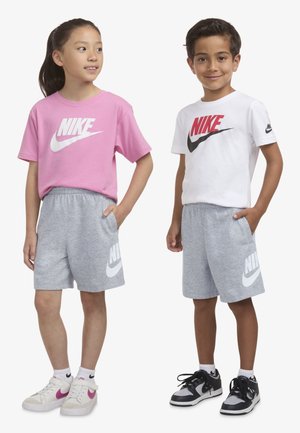 Zwei Kinder stehen nebeneinander. Das Mädchen trägt ein pinkes Nike-Shirt mit grauen Shorts, während der Junge ein weißes Nike-Shirt mit grauen Shorts anhat.