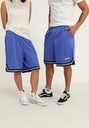 Blue athletic shorts with black and white striping, made from lightweight material. Paired with white and black sneakers.
