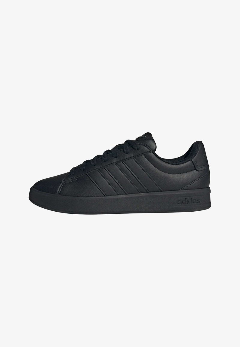 Zapatilla Adidas negra de corte bajo con tres franjas laterales, cierre frontal con cordones, cuello acolchado y suela de goma.
