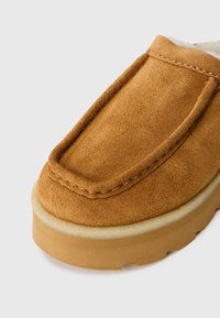 Suede instapschoen in bruin met een zachte, gestructureerde bovenkant. Heeft een gevoerde kraag en een stevige, flexibele rubberen zool.