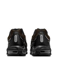 Ζευγάρι μαύρων και καφέ αθλητικών παπουτσιών Nike Air Max, εμφανιζόμενα από πίσω, με ορατές σόλες με αερόσακους και το κείμενο "MAXAIR" στις πίσω λωρίδες.