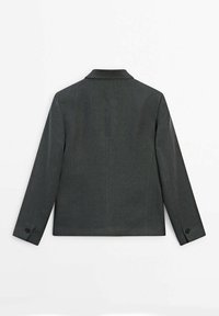 Blazer gris foncé sur mesure vu de dos avec manches longues et poignets boutonnés sur fond blanc.