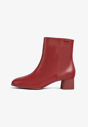 Červená kožená kotníková bota s blokovým podpatkem a hladkým povrchem, zdobená malou značkovou etiketou blízko horního okraje na vnější straně.