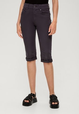 Pantalons cropped gris foncé en tissu doux, avec un ourlet roulé, des poches avant et un design ajusté. Associés à des sandales noires à lanières.