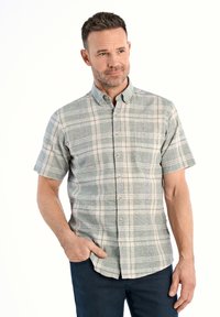 Camisa de cuadros de manga corta en verde claro, azul y beige. Cuenta con un cuello abotonado y un bolsillo en el pecho. Tejido suave con textura tejida.