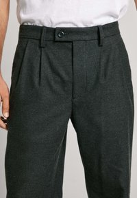 Tumšas pelēkas piegriezuma bikses no teksturēta auduma, ar krokām, pogu aizdari un sānu kabatām; šaurs piegriezums ar klasisku dizainu.