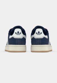 Σκούρα μπλε αθλητικά παπούτσια με λευκές λεπτομέρειες, κατασκευασμένα από υλικό με υφή, με στρογγυλή μύτη και λαστιχένια σόλα. Λογότυπο στη φτέρνα.