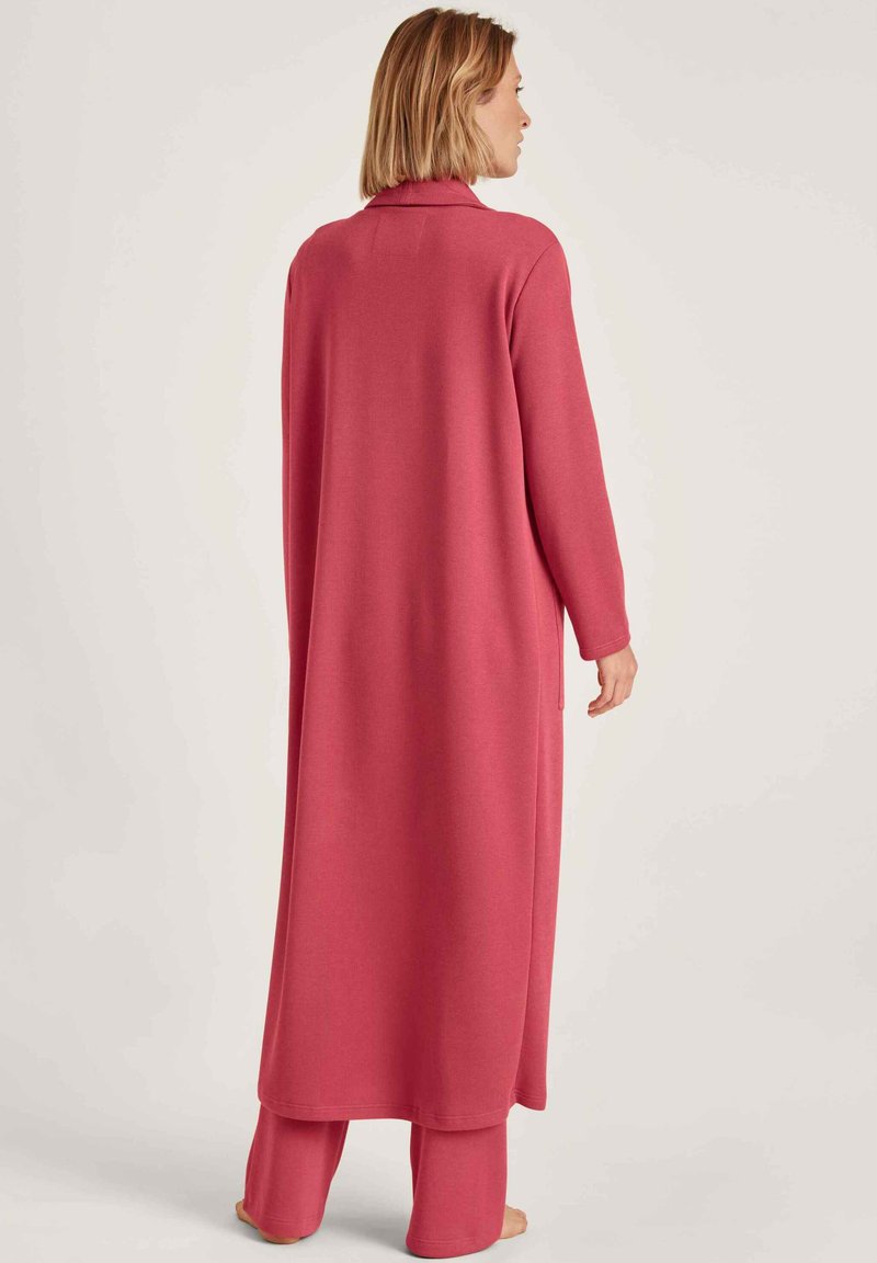 Langer, rosa Strickmantel mit einem Rollkragen-Design und langen Ärmeln, gerader Schnitt, seitlichen Schlitzen und einer strukturierten Oberfläche.