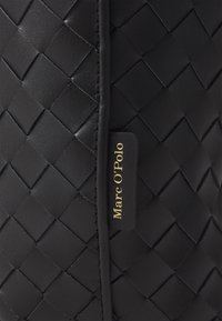 Sac en cuir tissé noir avec une surface texturée, une étiquette de logo embossée et des coutures contrastées le long des bords pour le détail.