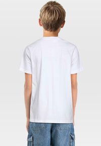 Vit bomullströja med rund halsringning och korta ärmar, med en slät yta. Baksidan har en enkel design utan logotyper eller mönster.