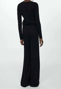 Conjunto de dos piezas de punto negro que incluye una blusa ajustada de manga larga y pantalones de pierna ancha con un patrón texturizado.