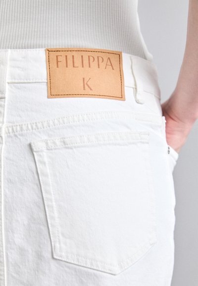 Biele džínsy z denimu s viditeľnou koženou visačkou s nápisom "FILIPPA K." Obsahujú dve zadné vrecká a šité detaily.