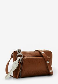 Borsa a tracolla in pelle marrone con hardware argentato, due scomparti con zip, logo impresso e finitura testurizzata. Presenta una tracolla removibile.