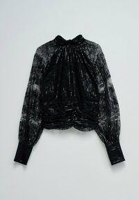 Sort langærmet bluse i lace med høj hals, gennemsigtige ærmer og mønster af perler hængende mod en hvid baggrund.