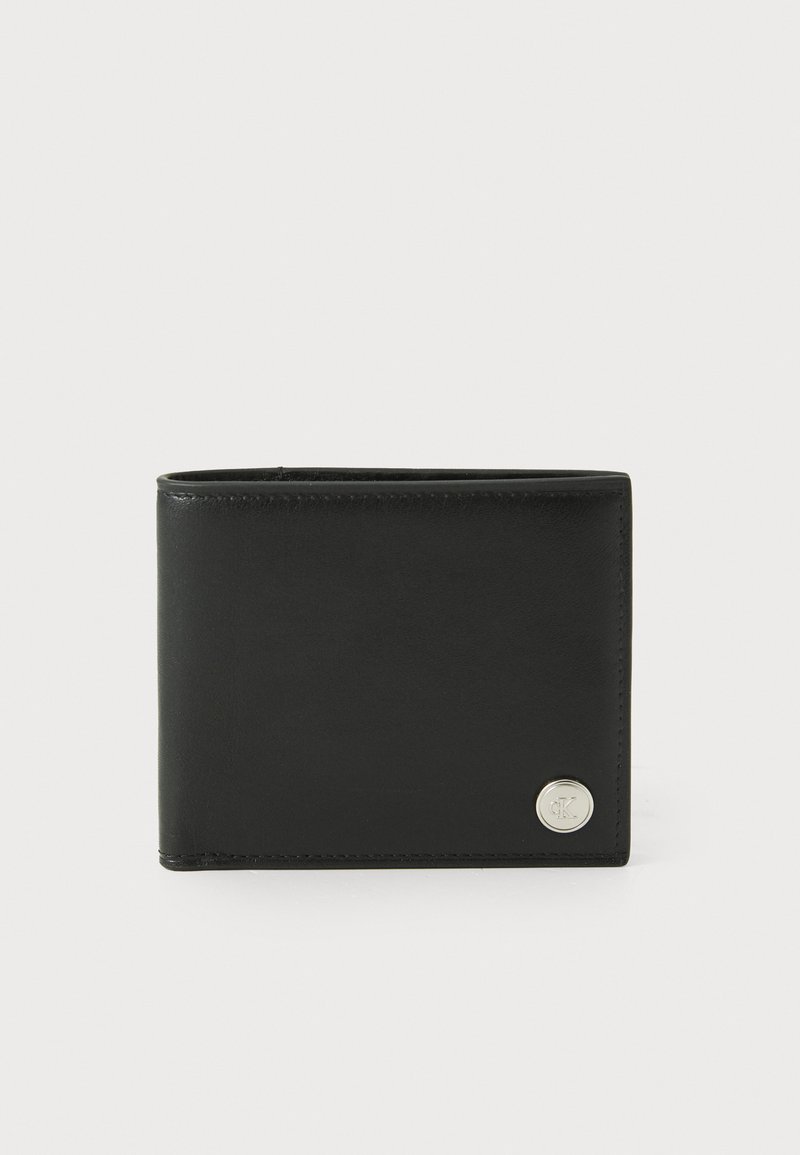 Portefeuille en cuir noir de forme rectangulaire et texture lisse. Se distingue par un accent logo circulaire en argent à l'avant.