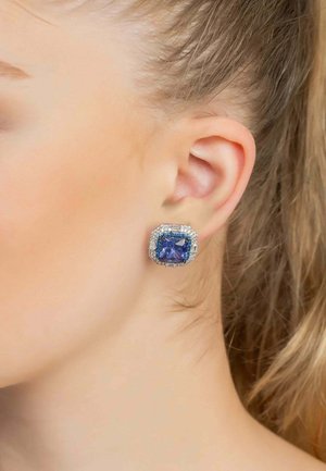 Square-shaped earring featuring a large blue stone, surrounded by small clear stones, set in silver-tone metal with a textured finish.