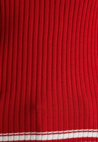 Tela de punto acanalada roja con líneas verticales y una franja blanca en el borde inferior. Textura suave, grosor medio.