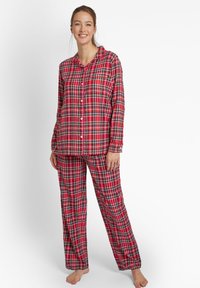 Set di pigiama a quadri rossi composto da una maglia a maniche lunghe con bottoni e pantaloni coordinati con un motivo a scacchi su tutta la superficie. Tessuto morbido, vestibilità comoda.
