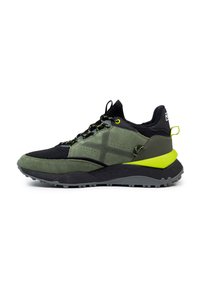 Zapatilla deportiva en verde oscuro y negro, con un upper texturizado, detalles reflectantes y un vibrante acento en el talón verde. La suela de goma es duradera.
