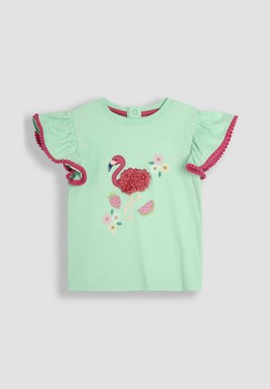 Jasnozielona koszulka z krótkim rękawem z różowymi falbaniastymi rękawami, haftem w kwiaty i owoce oraz wykończeniem z pomponami na rękawach.