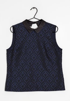 Ärmelloses marineblaues Top mit schwarzem geometrischem Muster und schwarzem spitzem Kragen, hängend an einem schwarzen Drahtbügel vor weißem Hintergrund.
