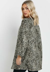 Tunic con stampa leopardata, maniche lunghe, tessuto leggero, vestibilità rilassata, base crema con macchie nere e marroni, scollatura a V e spacco laterale.