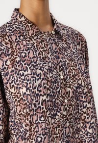 Leopardmønster skjorte med en myk tekstur, knappelukking og klassisk kragedesign i rosa, brune og marineblå toner.
