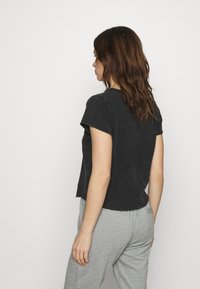 Melna kokvilnas T-krekls ar īsām piedurknēm, apaļu kakla izgriezumu un nedaudz īsu dizainu. Mīksta tekstūra, ar neapstrādātu malu apdari.