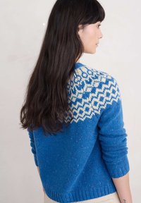 Sininen neulepusero, jossa on valkoinen geometrinen kuvio kaula-aukossa, teksturoitu kangas, resorit hihoissa ja rento istuvuus.