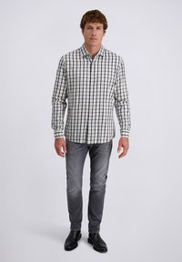 Kariertes Hemd mit grün-blauem Muster, langen Ärmeln und Kragen. Kombiniert mit grauen Jeans und schwarzen Stiefeln.