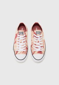 Tenisky Converse All Star majú vrchnú časť s tie-dye vzorom v odtieňoch ružovej a krémovej, biele šnúrky a čiernu gumovú podrážku s bielym vrchom.